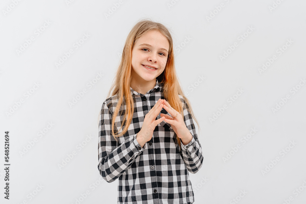 Lovely teen girl in in casual plaid shirt, rubs hands and smiles, relish smth good, looks happy, stands over white background Lovely teen girl in in casual plaid shirt, rubs hands and smiles, relish smth good, looks happy, stands over white background
