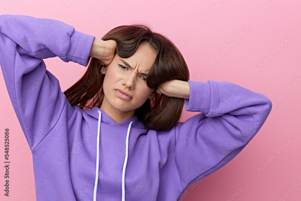 a disgruntled woman stands full-face on a pink background in a purple suit, frowning, straightens her loose long hair with two hands, slightly lifting them a disgruntled woman stands full-face on a pink background in a purple suit, frowning, straightens her loose long hair with two hands, slightly lifting them
