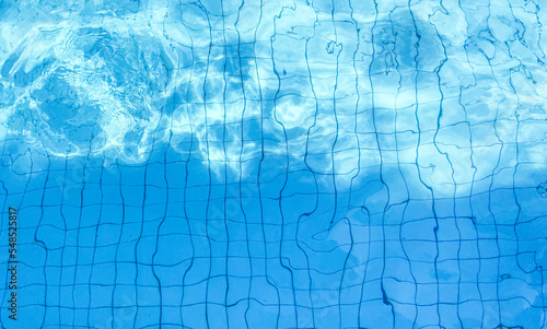 blue water wave pattern in swimming pool as the sun shines down during the day. Soft and selective focus.