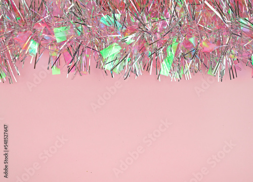 Shiny pink and silver tinsel on a pink background.Blank space for text. Fancy Christmas background.