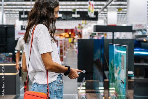 Focused woman choosing a tv in a tech store photo