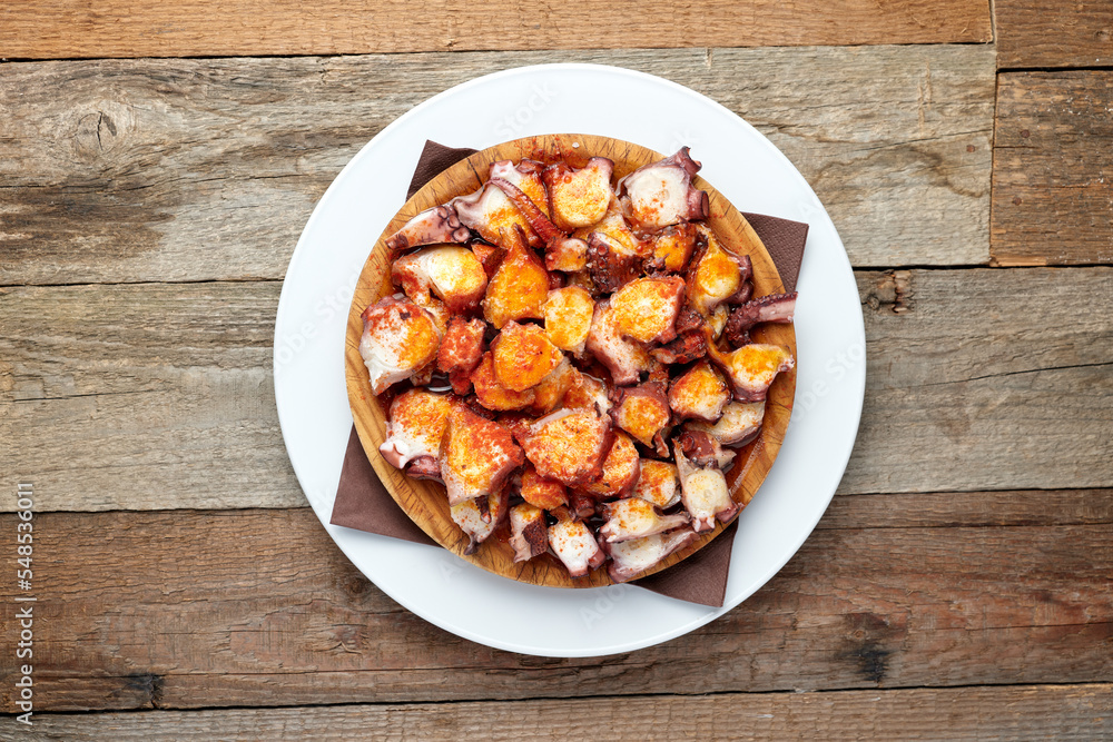 top view of a plate of octopus with olive oil and paprika, isolated on a wooden table top view of a plate of octopus with olive oil and paprika, isolated on a wooden table