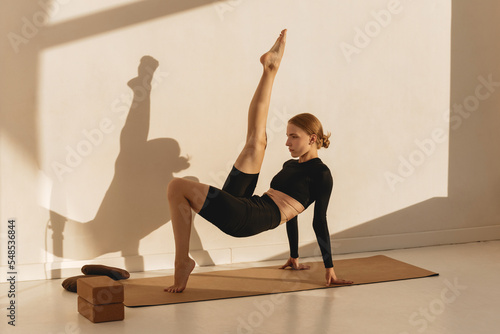 Wellness exercise, woman on floor mat stretching alone, workout day. Fitness training motivation in sunlight, health instructor stretching  and athlete balance lifestyle