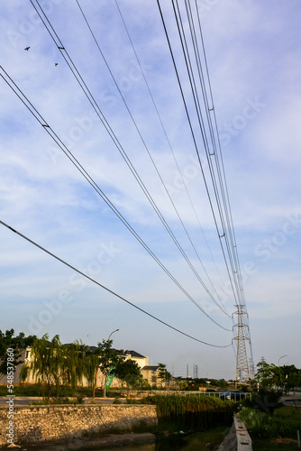 long black electrical wires running under a cloudy clear blue sky