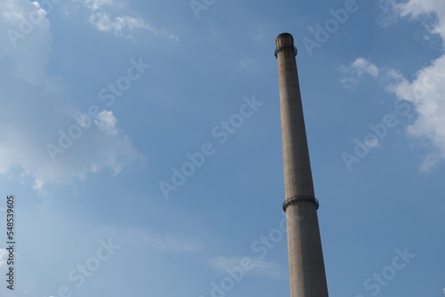 one long factory cement chimney and blue sunny sky