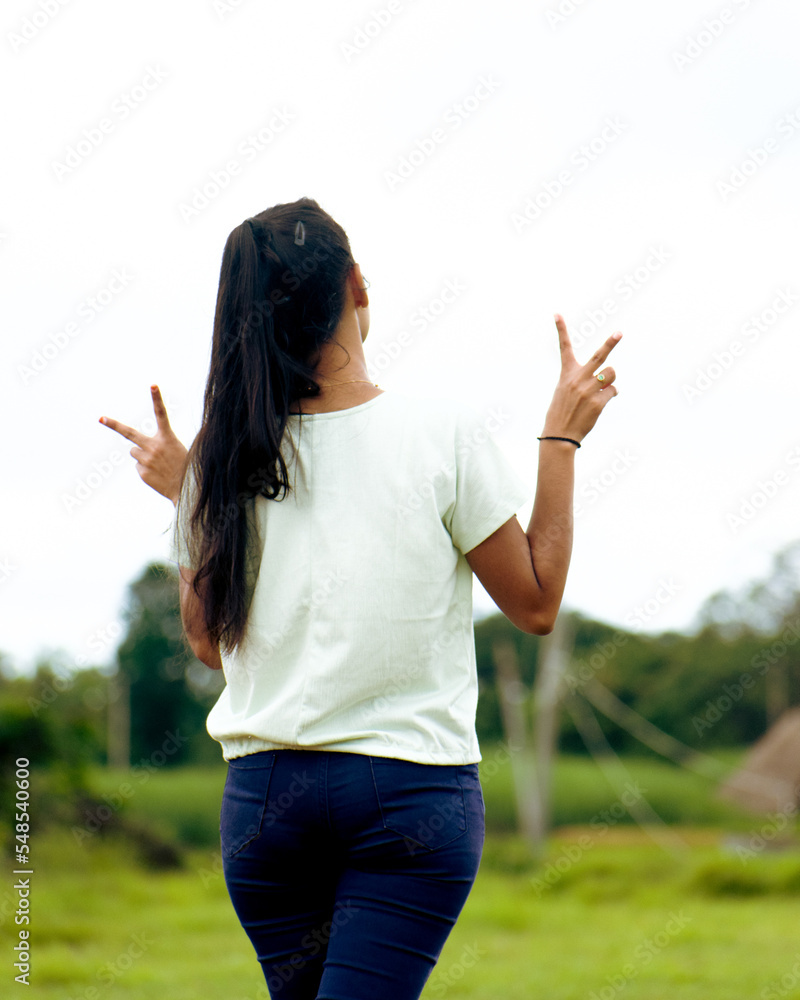 Young attractive model showing peace gesture with both hands from behind. Young attractive model showing peace gesture with both hands from behind.