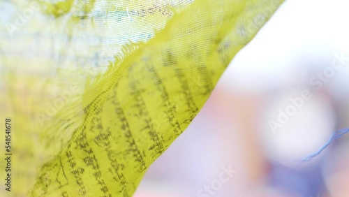 Closeup of a yellow prayer flag moving in the wind.
