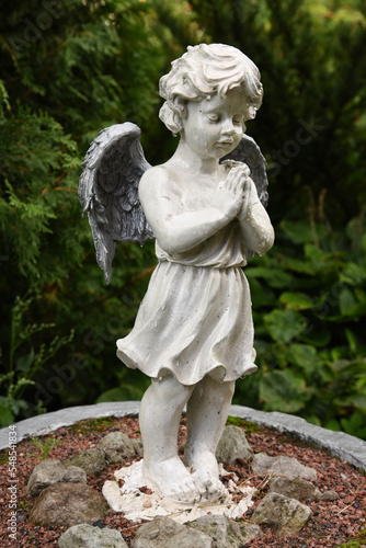 A wet statue of a little angel in the garden of a convent in the Russian city of Volkhov.