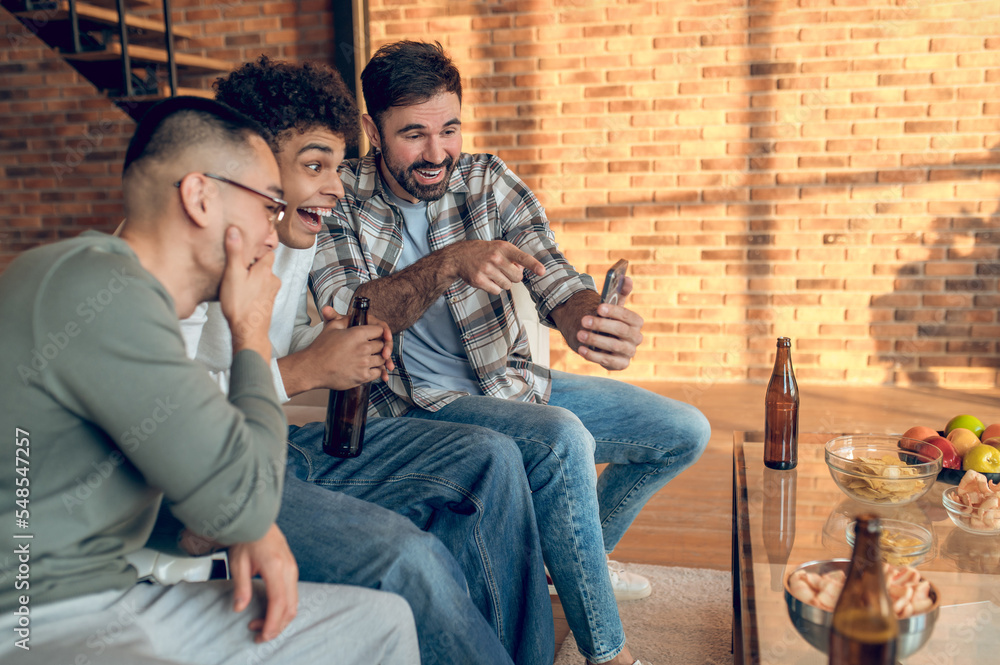 Company of buddies viewing selfies on the smartphone Company of buddies viewing selfies on the smartphone