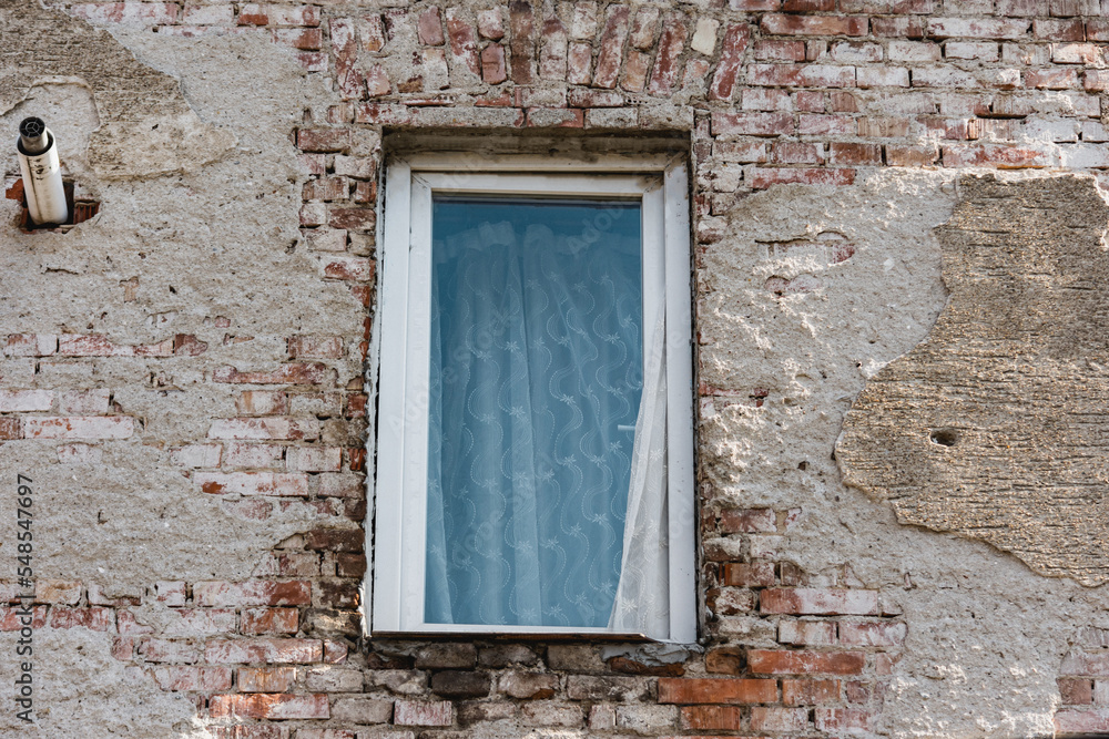 Unfinished home phase with a thermal window system covered with an old white curtain Unfinished home phase with a thermal window system covered with an old white curtain