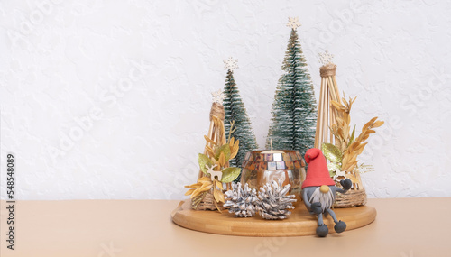 Christmas New Year still life with gnome, deer, XMAS trees and candle at home interior. Copy space.