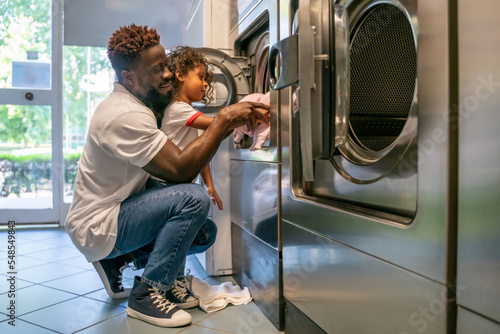 Slika na platnu Father and daughter loading laundry into a washer
