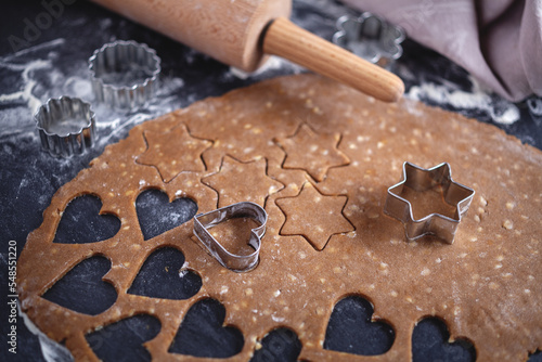 Weihnachtsbäckerei - aus Lebkuchenteig werden auf dunklem Untergrund weihnachtliche Motive ausgestochen  photo