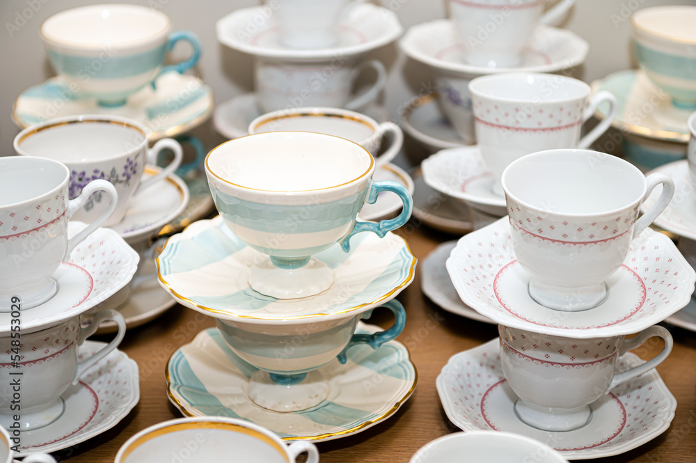 Close up of coffee and tea cups with plates lined up on party table Close up of coffee and tea cups with plates lined up on party table