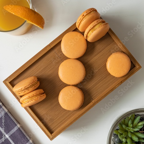 Top view of orange-colored French macarons in a wooden box on a table