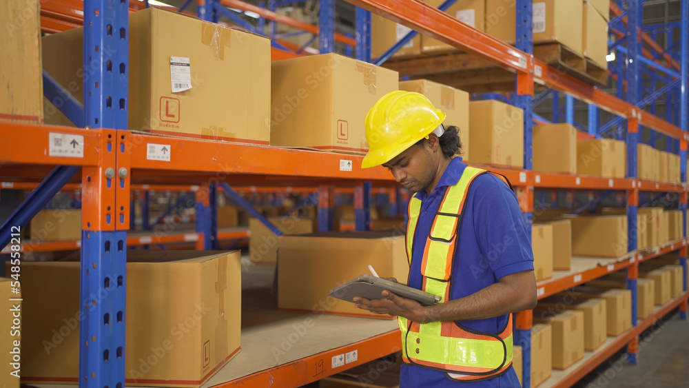 Portrait of Indian worker working in large warehouse retail store industry. Rack of stock storage. Interior of cargo in ecommerce and logistic concept. Depot. People lifestyle. Shipment service. Portrait of Indian worker working in large warehouse retail store industry. Rack of stock storage. Interior of cargo in ecommerce and logistic concept. Depot. People lifestyle. Shipment service.
