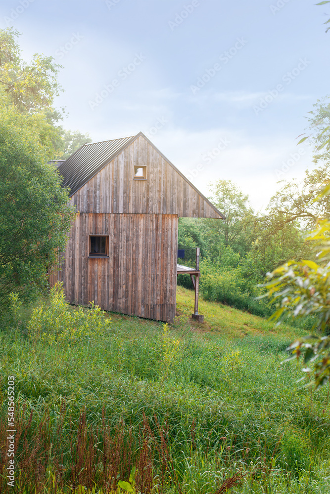 Obraz premium wooden modern cabin in the frest facing green valley