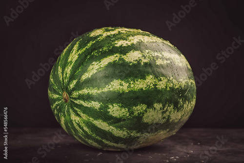 Closeup of whole wet round watermelon on blur wooden counter