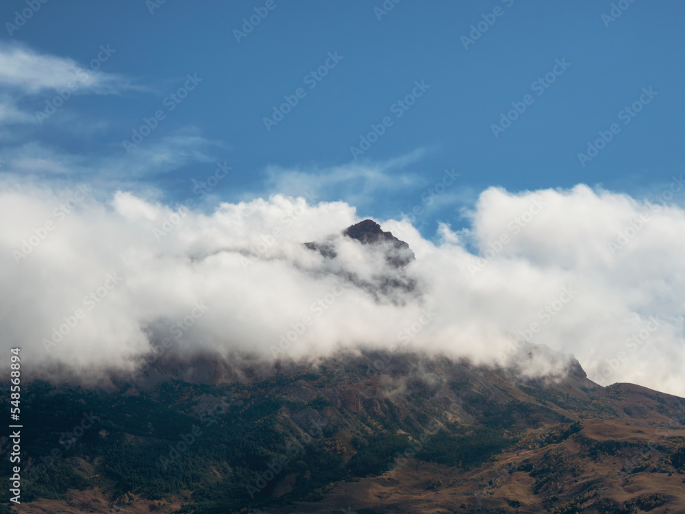 Mountain in the white clouds. Mystical landscape with beautiful sharp rocks in low clouds. Beautiful mountain foggy scenery on abyss edge with sharp stones.