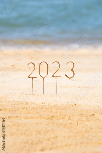 Numbers 2023 for the upcoming New Year among the waves on a sunny beach. Celebration concept in exotic country