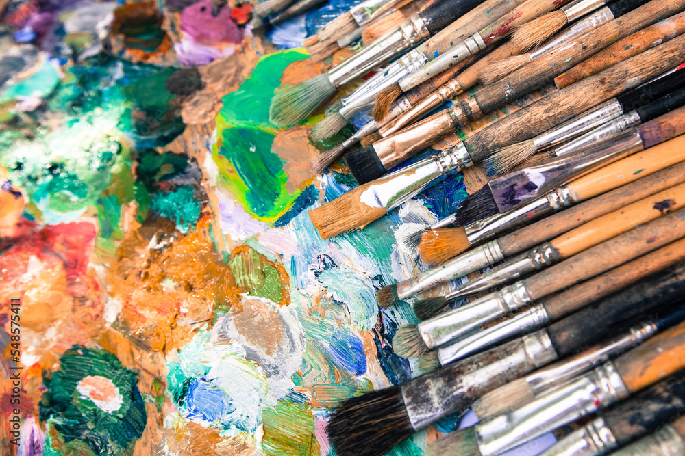 Obraz premium Row artists of Paintbrushes with different sizes lying on the dirty artistic palettes with free space on top,background for creative art design (workspace), close, horizontal image