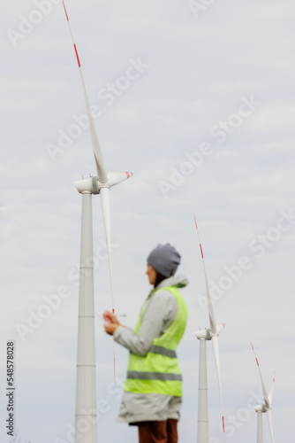 female engineer in a protective vest takes measurements of the speed of wind turbines. electricity is generated by wind. technologies without an eco trace. engineering solution. generating electricity