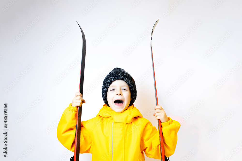 happy little boy with skis in his hands on a white background