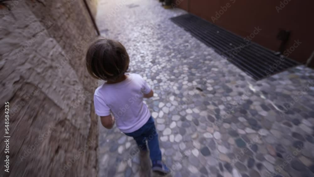 One happy small boy running on cobblestone European street in Italian alley. Child runner seen from above One happy small boy running on cobblestone European street in Italian alley. Child runner seen from above
