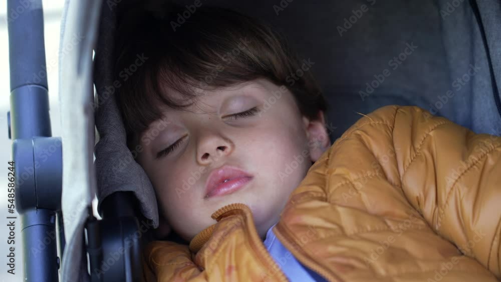One little boy asleep sitting in stroller. Closeup child face sleeping wearing jacket. Kid napping in afternoon One little boy asleep sitting in stroller. Closeup child face sleeping wearing jacket. Kid napping in afternoon