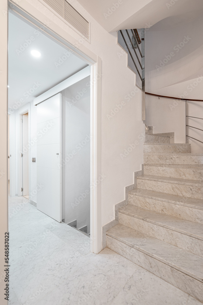 Spiral stairway with white stairs and railing on wall inside of modern apartment with corridor. Spiral stairway with white stairs and railing on wall inside of modern apartment with corridor.