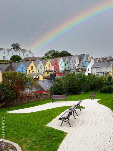 A rainbow on a cloudy day, with a park in the foreground in the city of Cobh, Ireland