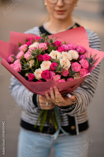 close-up view on bouquet with roses and thistles in hands of woman
