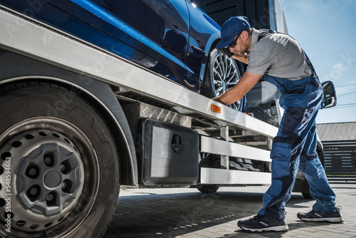 Professional Tow Truck Driver Fastening the Car for Safe Transportation © Tomasz Zajda