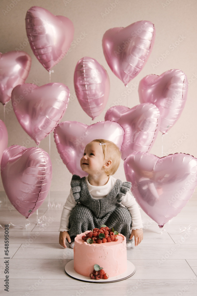 Cute little girl, 1st birthday, baby with pink heart balloons and birthday cake