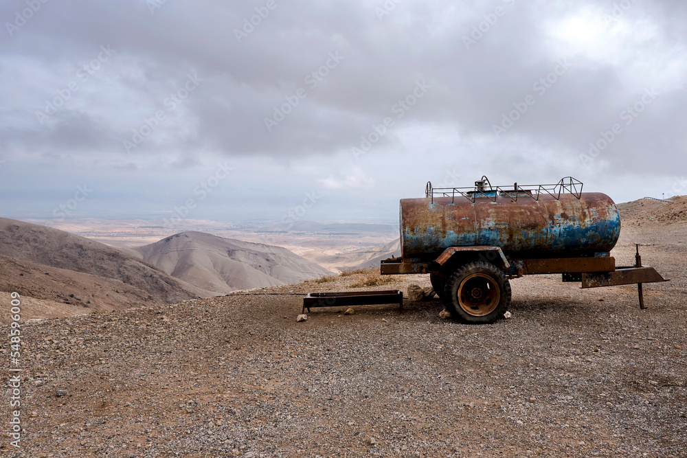 Obraz premium Rusty water tanker truck placed on the side of the gravel road in the desert, near Jericho city. West Bank
