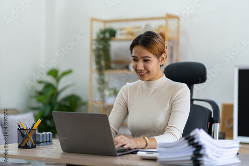 Portrait of an Asian businesswoman thinking View financial statements and make marketing plans, review documents, calculate numbers and record information in a notebook.
