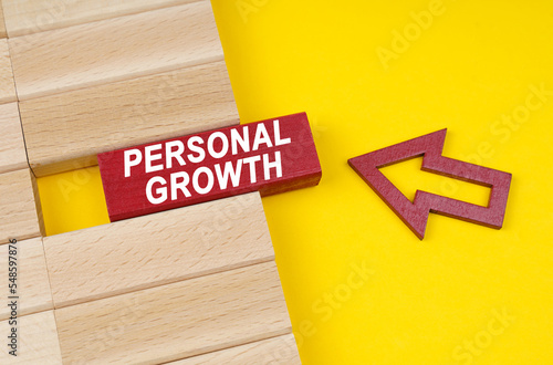 On a yellow surface are wooden blocks and an arrow pointing to a block with the inscription - personal growth photo