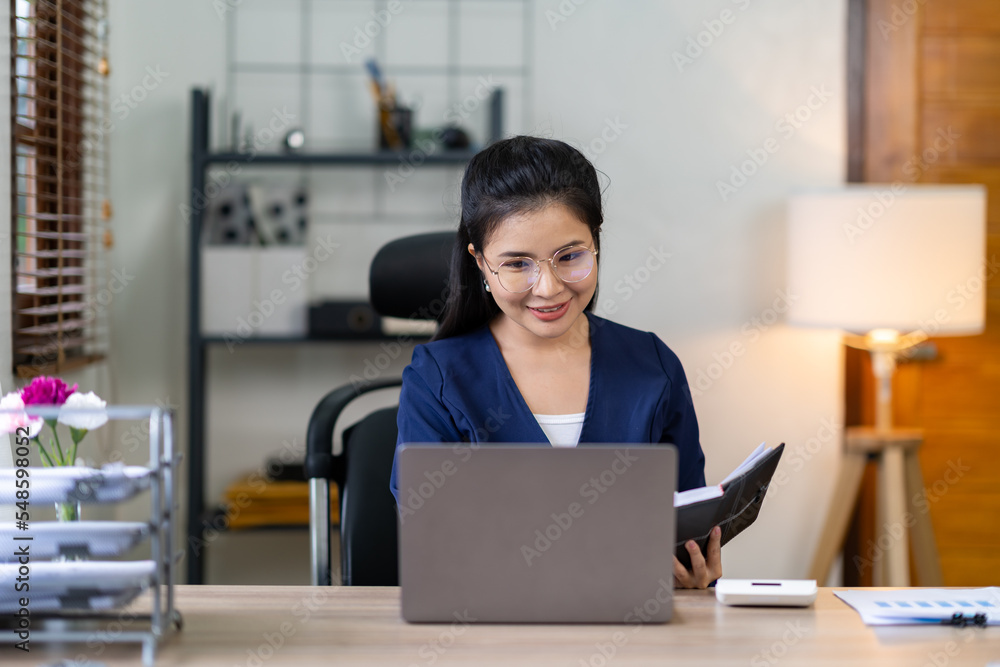Portrait of a beautiful and attractive Asian businesswoman smiling and taking notes. Guidelines for doing business, finance, and marketing. Portrait of a beautiful and attractive Asian businesswoman smiling and taking notes. Guidelines for doing business, finance, and marketing.