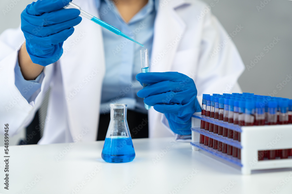 An Asian female scientist or doctor drops a reagent into a test tube on a shelf for analysis research concept. An Asian female scientist or doctor drops a reagent into a test tube on a shelf for analysis research concept.