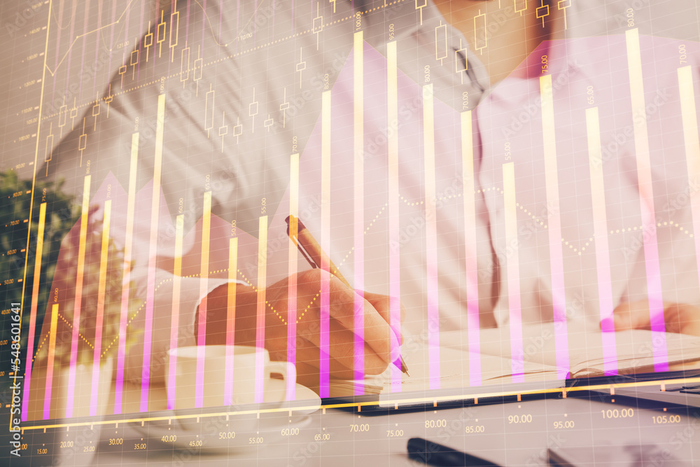 Double exposure of man's hands writing notes of stock market with forex chart.