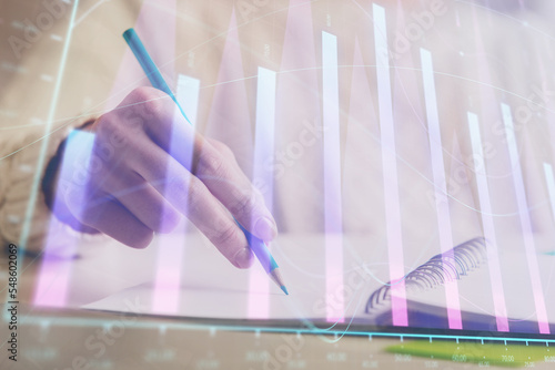 Financial forex graph displayed on hands taking notes background. Concept of research. Double exposure © peshkova