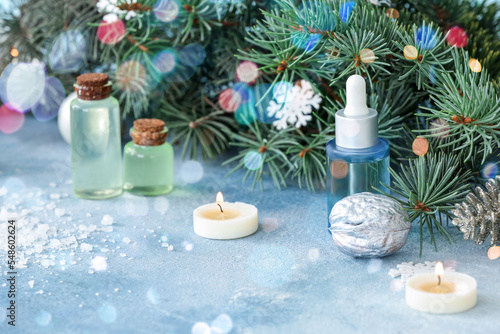 Essential oils, candles and Christmas decor on light blue background