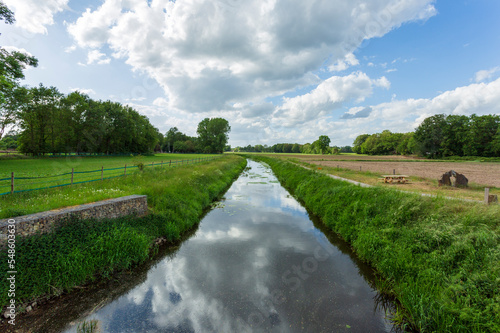 green meadows on a cloudy day and cloud reflections in the river. Parks and nature landscapes in Europe, Gronau, Germany 