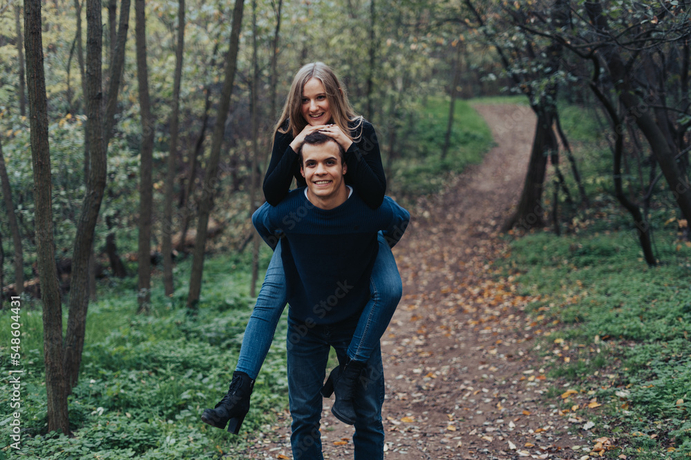 Young cheerful couple having fun while piggybacking in a forest Young cheerful couple having fun while piggybacking in a forest