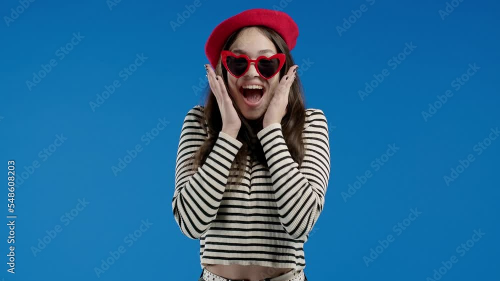 French woman is very glad, she screaming wow loud. Lady trying to get attention. Concept of black friday sales, profitable offer. Excited happy girl on blue background. French woman is very glad, she screaming wow loud. Lady trying to get attention. Concept of black friday sales, profitable offer. Excited happy girl on blue background.