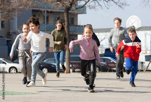 Kids spending time together outdoors running on square at warm spring day