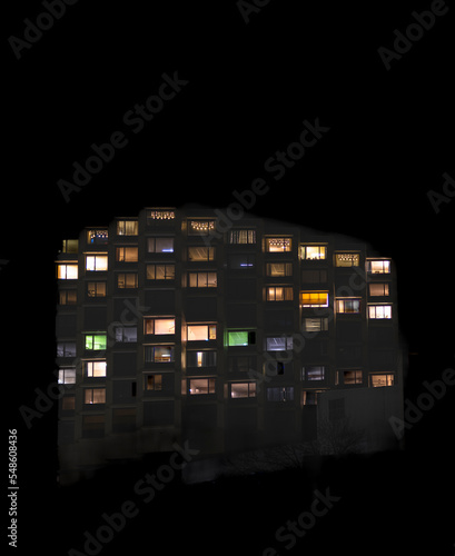 Frontal view of the night facade of building with a lot of windows with people staying at home during quarantine.. The illuminated windows of a large building on a dark night.