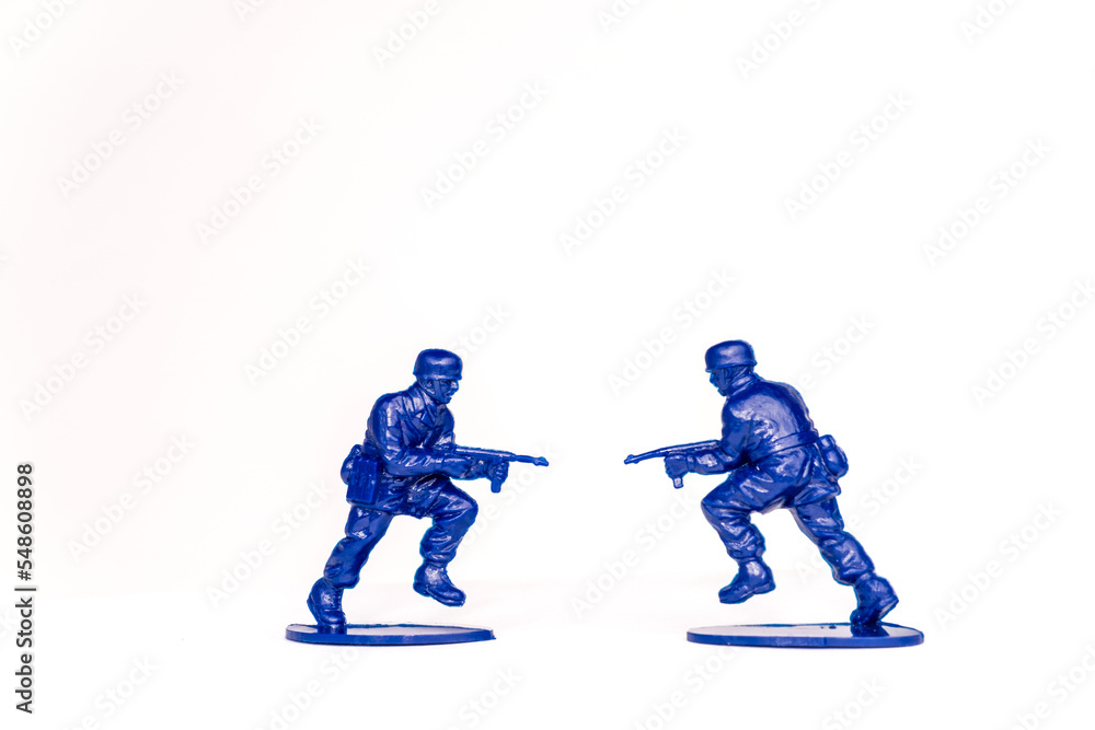 Obraz premium two toy soldiers pointing guns at each other in front of a white background. Ukraine and Russia war, no war, military equipment and soldiering.
