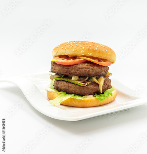 A large burger with a double cutlet, grilled vegetables and sauce. Isolate on a white background, ready-made menu