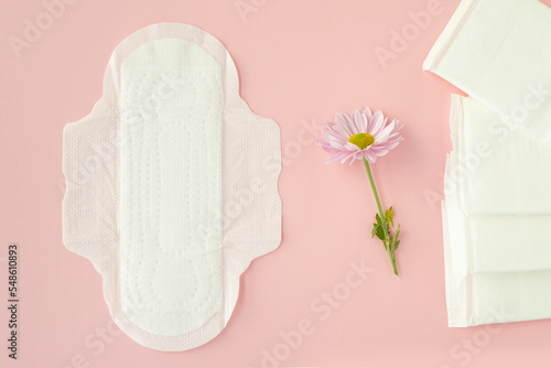 Sanitary pads and flowers on pink background. Concept of critical days, menstruation